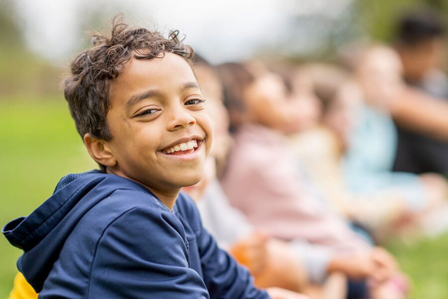 young boy smiling outside with friends after pediatric neurosurgery in New Jersey