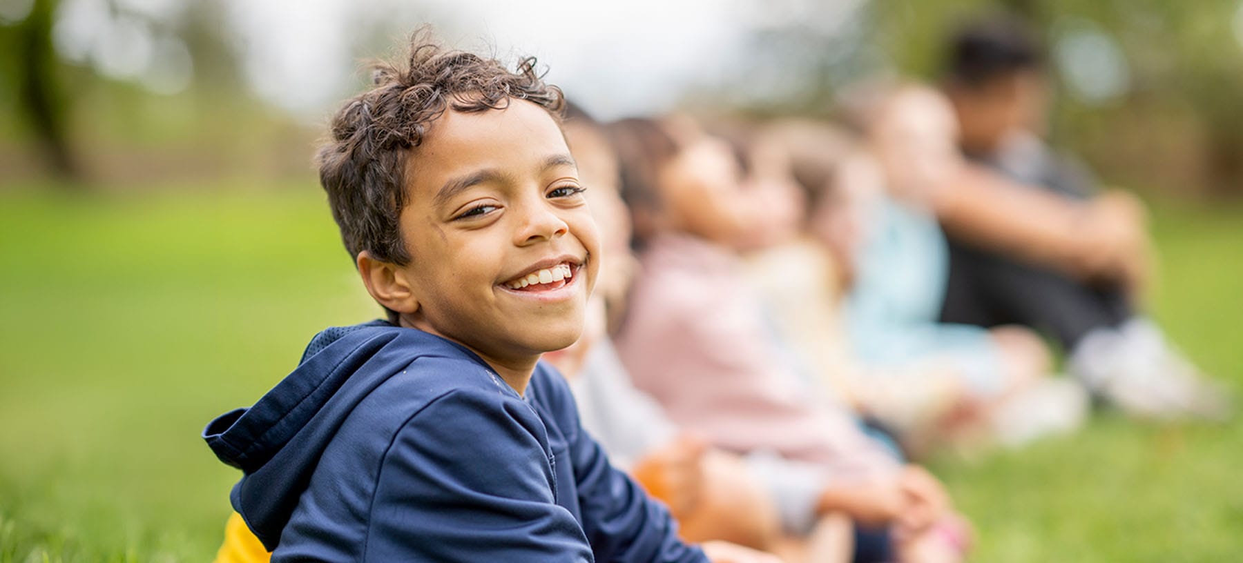 young boy smiling outside with friends after pediatric neurosurgery in New Jersey